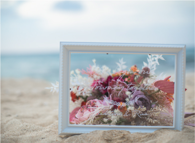 砂浜に置かれた花束と額縁の写真